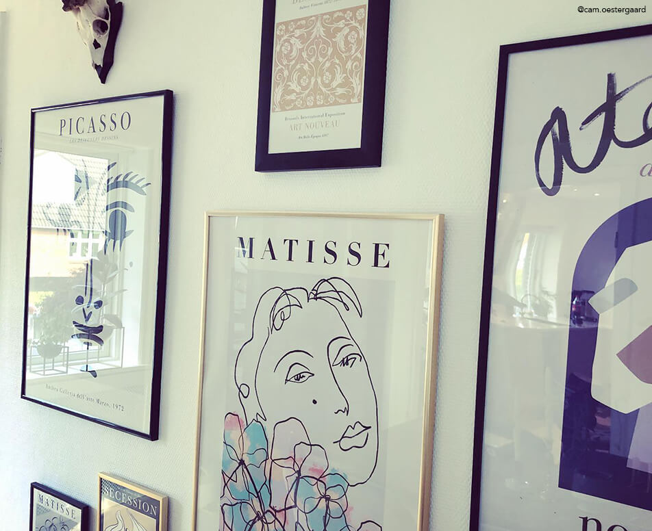 Tavelvägg med svarta ramar och guldramar