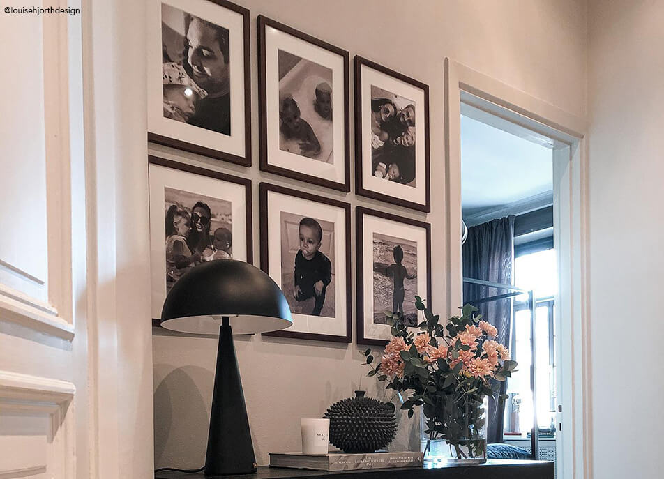 Fotovägg i hall, svartvita foton i mörka träramar