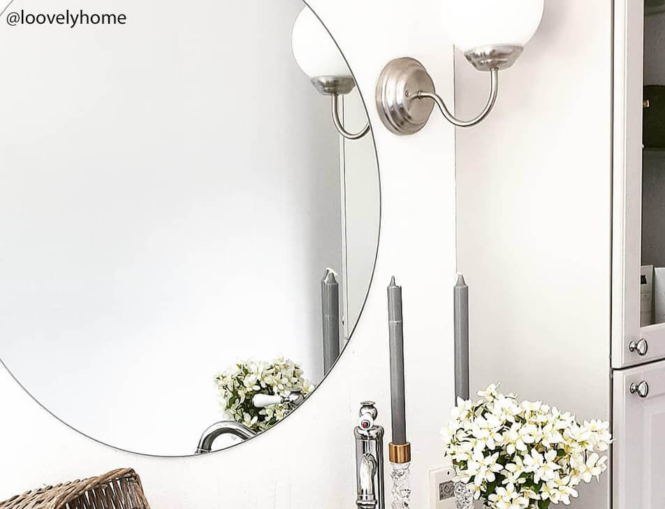 Kulaté zrcadlo, květiny a svíčka v koupelně